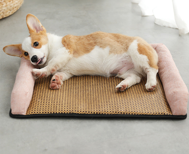 Corgi lying on a woven pet mat with pink sides on a concrete floor.