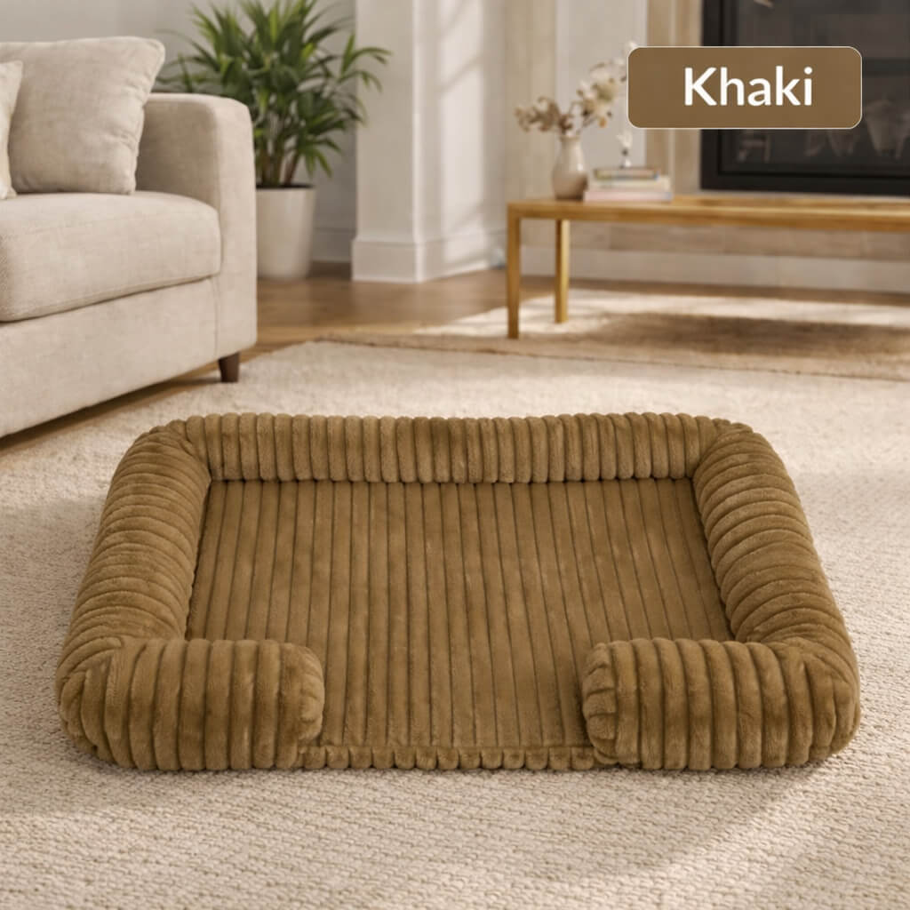 Khaki Orthopedic Joint Support Dog Bed in a living room setting with a couch and TV in the background.