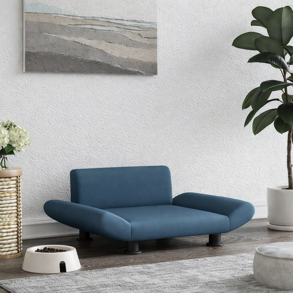 Modern blue pet sofa in a living room with a plant and artwork on the wall.